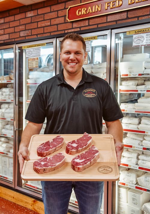 Employee holding cutting board with steaks