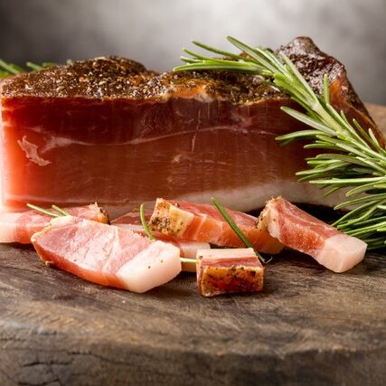 photo of delicious smoked ham on wooden table with rosemary